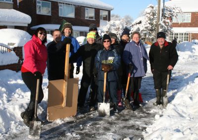 A group of volunteers clearing snow from a footpath