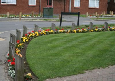 A flower bed in full bloom edging a manicured grass area in the centre of Messingham