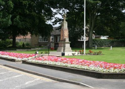Flower beds in full bloom in the foreground of the Messingham War Memorial