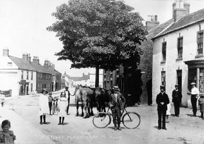 A vintage photograph showing Messingham High Street with a number of villagers milling about